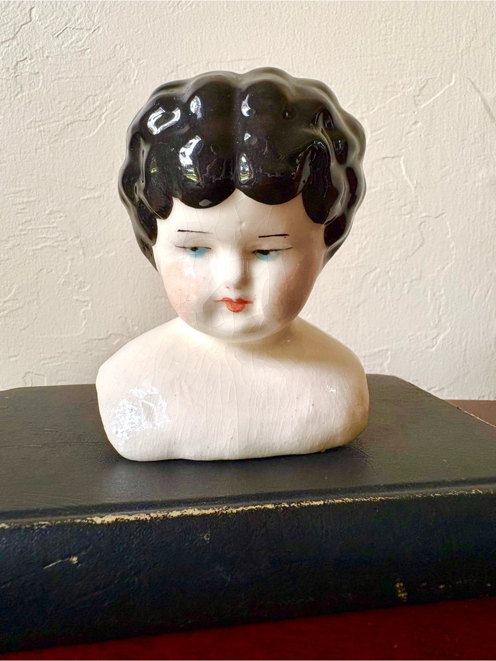 Vintage porcelain doll head bust with black molded hair and painted blue eyes
